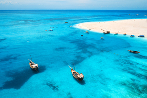 Aerial view of fishing boats on tropical sea coast with transparent blue water and sandy beach at sunny day. Summer holiday. Indian Ocean in Zanzibar, Africa. Landscape with boat, white sand. Top view