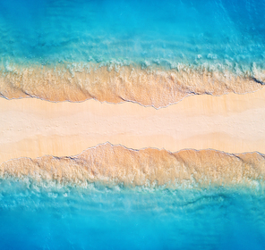 Aerial view of transparent blue sea with waves on the both sides and empty sandy beach at sunset. Summer holiday in Zanzibar, Africa. Tropical landscape with lagoon, white sand and ocean. Top view