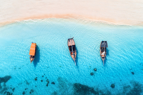 aerial view of the fishing boats in clear blue water at  in summer. top view from drone of boat, yacht, sandy beach in zanzibar. travel. tropical seascape with sailboats, sea. view from above