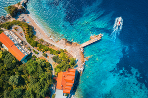 Aerial view of sea coast with clear blue water, boats, pier, hotels and green trees in summer at sunny day in Croatia. Top view of sandy beach, floating yacht, buildings and forest. Travel