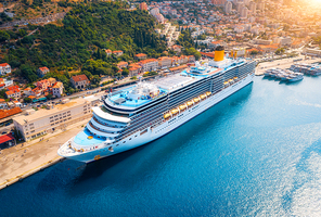 Aerial view of cruise ship in port at sunset in Dubrovnik, Croatia. Beautiful ships, boats and yachts. Landscape with harbor, city, mountains, blue sea. Luxury cruise. Top view of floating liner