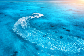 Aerial view of floating water scooter in blue water at sunset in summer. Holiday in Indian ocean, Zanzibar, Africa. Top view of jet ski in motion. Tropical seascape with moving motorboat. Extreme