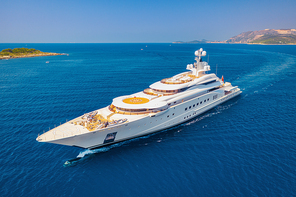 Aerial view of luxury yacht and blue sea at sunny bright day in summer. Big white modern boat. Top view of beautiful futuristic yacht, bay, mountains, clear water, sky. Travel in Croatia. Adriatic sea