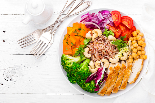 buddha bowl dish with chicken fillet, brown food, pepper, tomato, broccoli, onion, chickpea, fresh lettuce salad, cashew and walnuts. healthy balanced eating. top view. white background