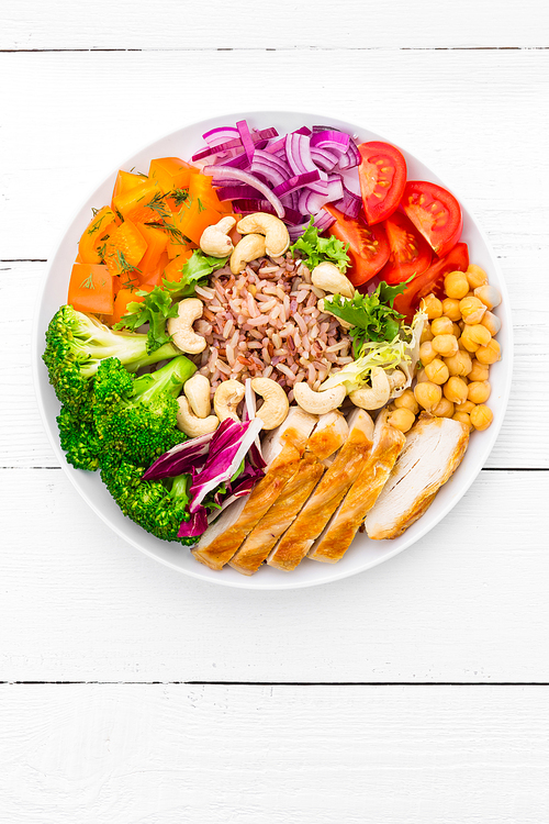buddha bowl dish with chicken fillet, brown food, pepper, tomato, broccoli, onion, chickpea, fresh lettuce salad, cashew and walnuts. healthy balanced eating. top view. white background