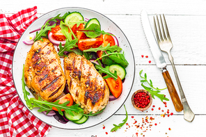 Grilled chicken breast. Fried chicken fillet and fresh vegetable salad of tomatoes, cucumbers and arugula leaves. Chicken meat salad. Healthy food. Flat lay. Top view. White background