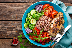 Grilled chicken breast. Fried chicken fillet and fresh vegetable salad of tomatoes, cucumbers, pepper, lettuce and arugula leaves. Chicken meat with salad. Healthy food. Flat lay. Top view. Wooden background