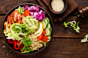 Buddha bowl dish. Healthy balanced lunch with quinoa, grilled chicken meat, lettuce salad, pepper, cucumber, tomato and avocado guacamole with lemon