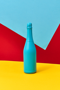Creative blue painted holiday wine bottle mock up on a tricolor blue red yellow background with copy space. Minimalism concept.