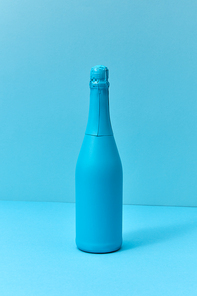 Monotone blue composition painted champagne mock up bottle with soft shadows with copy space. Minimal concept.