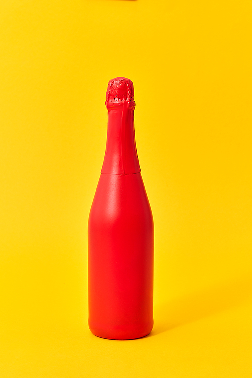 Decorative painted red wine bottle mock up on an yellow background with copy space. Minimal concept.