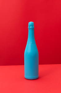 Holiday mock up bottle of champagne red painted spray on a duotone red background with copy space. Minimal concept.