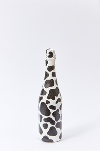 Decorative white painted champagne bottle with black stains on a light grey background, copy space. Minimalism concept.