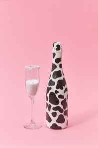 Holiday glass of white powder as a sugar and painted bottle with black spots on a light millennial pink background, copy space. Congratulation card.