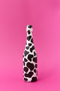 Creative white painted champagne bottle with black spots on a hot pink background, place for text. Minimalism concept.