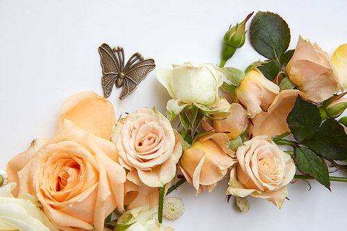 Close up of orange flowers with metal butterfly over white background