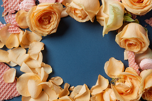 Frame made of waffles and roses as decoration on navy blue background. Circle in center may be used for any ideas, emotions, concepts. Valentine's Day concept.