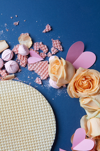 Valentine's Day concept. Closeup of roses and waffles represented on navy blue background. Waffles and roses with many hearts used for decoration of background.