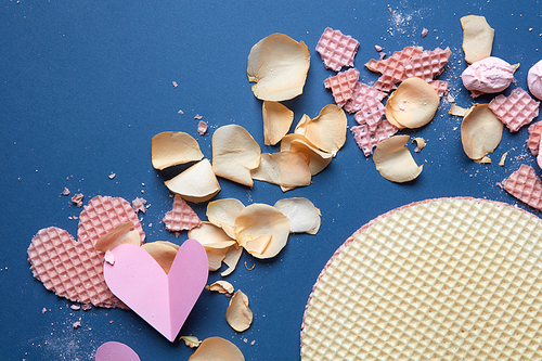 beautiful Valentine background with rose petals, paper and wafer hearts on a blue background