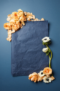 flowers and a piece of black paper in a frame with space for text on a dark background, flat lay