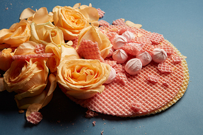 Circle waffles with orange roses. Waffles as decoration of navy blue background. Many roses of orange color represented on waffles.