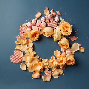 Beautiful round frame of roses, and meringue wafer hearts with room for text on dark background, flat lay