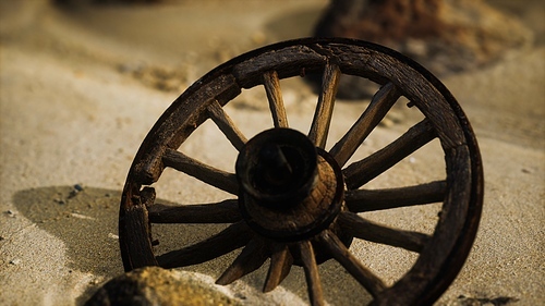 Large wooden wheel in the sand