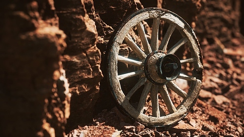 old wooden cart wheel on stone rocks