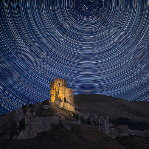 Digital composite image of star trails around Polaris with Medieval castle ruins in Autumn landscape