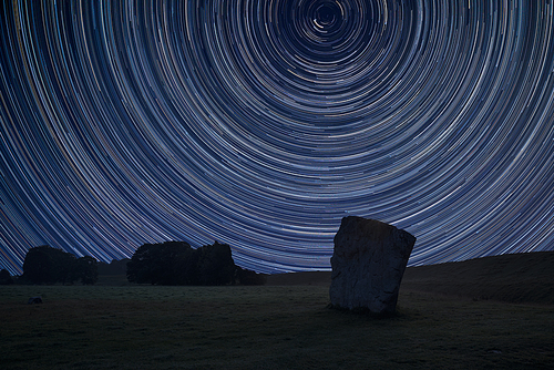 Digital composite image of star trails around Polaris with Beautiful Summer landscape of Neolithic standing stones in English countryside