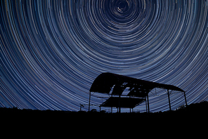Digital composite image of star trails around Polaris with Beautiful landscape image of old derelict barn silhouette