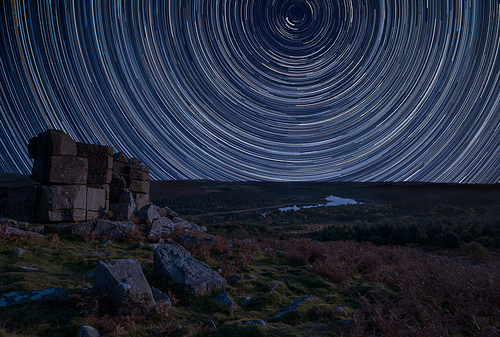 Digital composite image of star trails around Polaris with Stunning vibrant Beautiful landscape image of view from Leather Tor in Dartmoor National Park