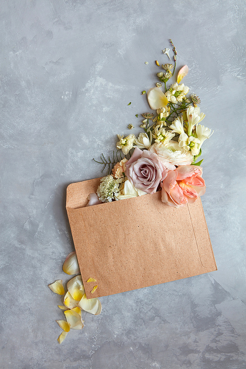 The message in the letter. Beautiful bouquet of flowers in an envelope on a stone gray background as a concept for the holiday, Flat lay.