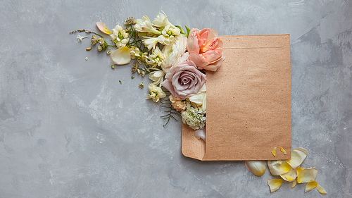 beautiful flowers in envelope on a stone gray background. Top view