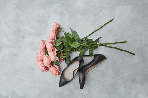 elegant black female shoes and a bouquet of pink roses on a gray background, the concept of Valentine's Day,