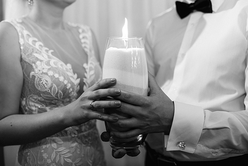 groom puts bride on wedding candle