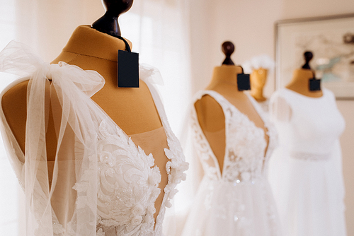 beautiful white wedding dresses hang on mannequins