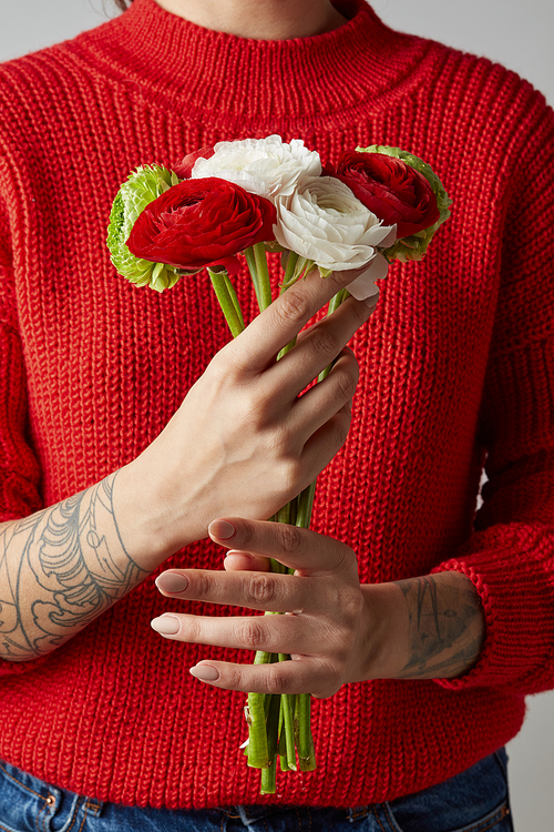 girl with a tattoo on her hands in a red knitted sweater holds a bouquet of flowers. a happy Valentine's day