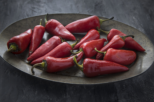A close up studio photo of red chili peppers on a platter.