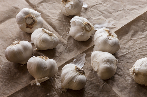 Close up of raw garlic bulbs on brown paper.