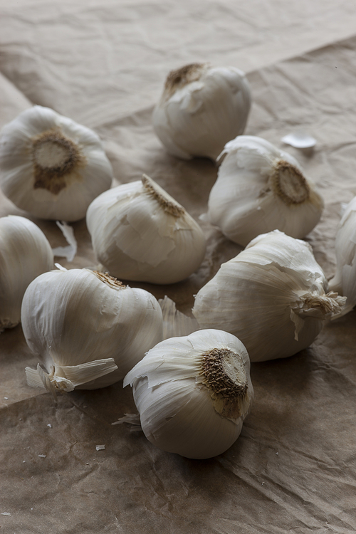 Close up of raw garlic bulbs on brown paper.