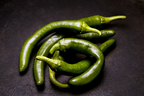 A studio photo of a pile of raw green chili peppers.