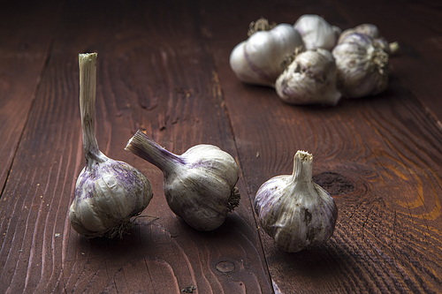 Fine art photograph of garlic bulbs displayed on an old wood table.
