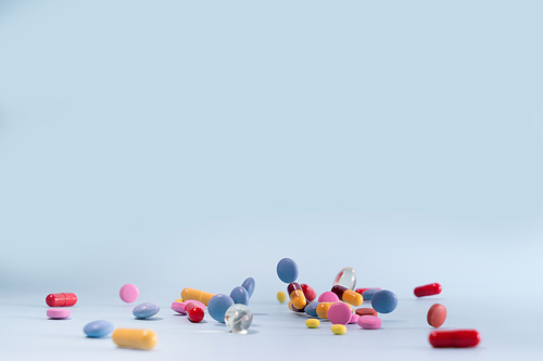 Pile of colorful medical pills on blue background, top view