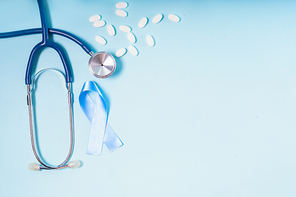 White pills, blue Diabetes Awareness Ribbon with stethoscope on blue background, copy space