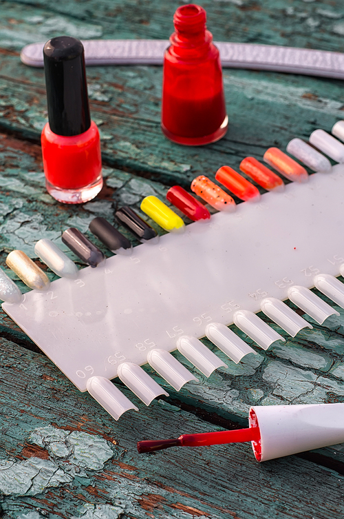 Tubes with varnish for nail polish of different colors on an old wooden background