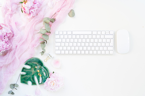 Flat lay home office workspace - modern keyboard with female accessories and fresh peony flowers