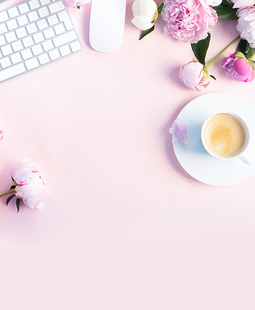 Flat lay home office workspace - modern keyboard with female accessories and fresh peony flowers, copy space on pink desk background