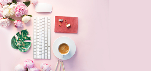 Flat lay home office workspace - modern keyboard with cup of coffee, office supplies and peony flowers, copy space on pink background banner