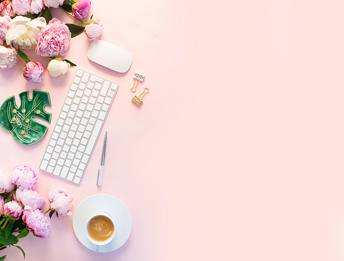 Flat lay home office workspace - modern white keyboard with cup of coffee and peony flowers, copy space on pink plain background